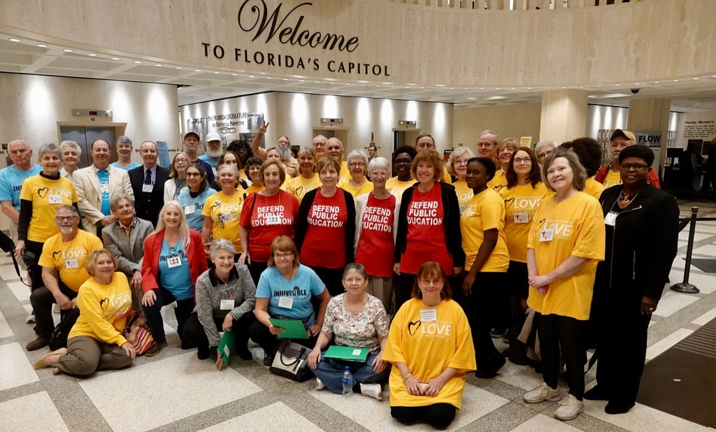 A crowd of UU members standing in a building with the words "Welcome to Florida's Capitol" behind them.